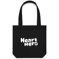 Heart Foundation black canvas tote bag shown with vintage look Heart hero text in white print on the front