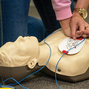 A woman practicing CPR on a thrust CPR mannikin